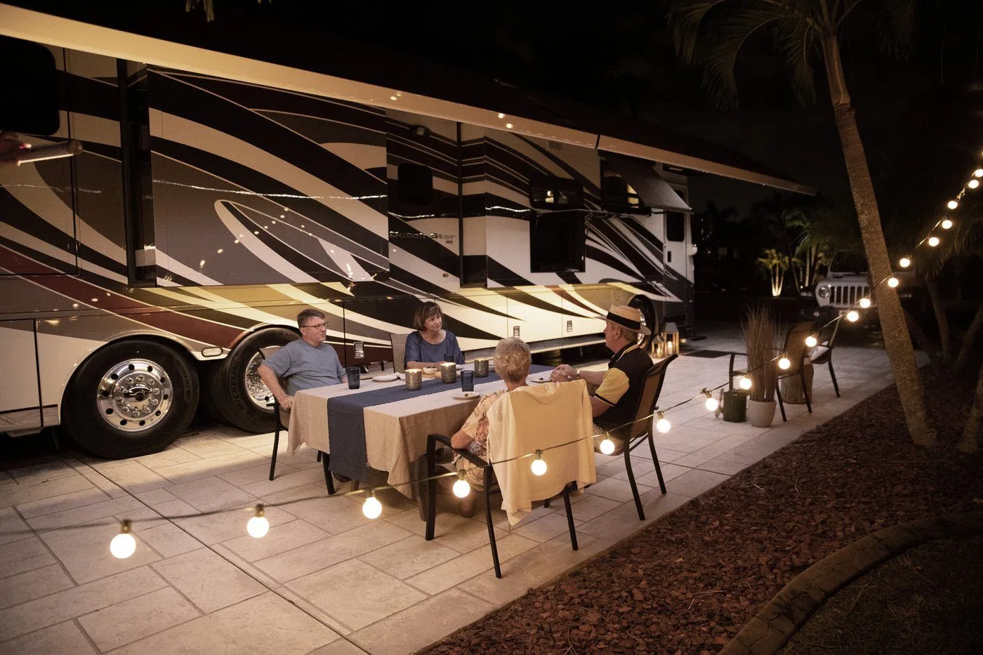 Newmar owners dining together outside their coach at night
